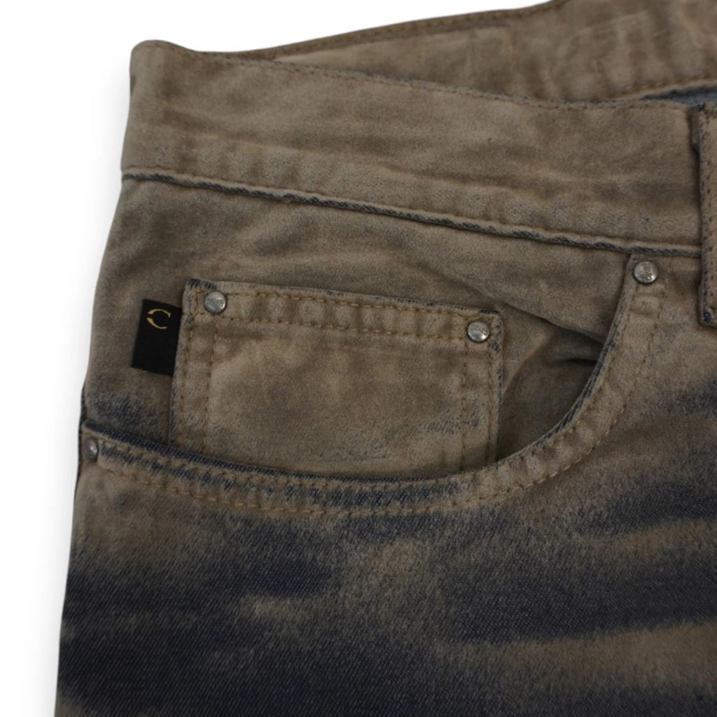 Foto macro del taschino anteriore dei jeans con micro etichetta nera ricamata con il monogramma circolare Just Cavalli e rivetti metallici.