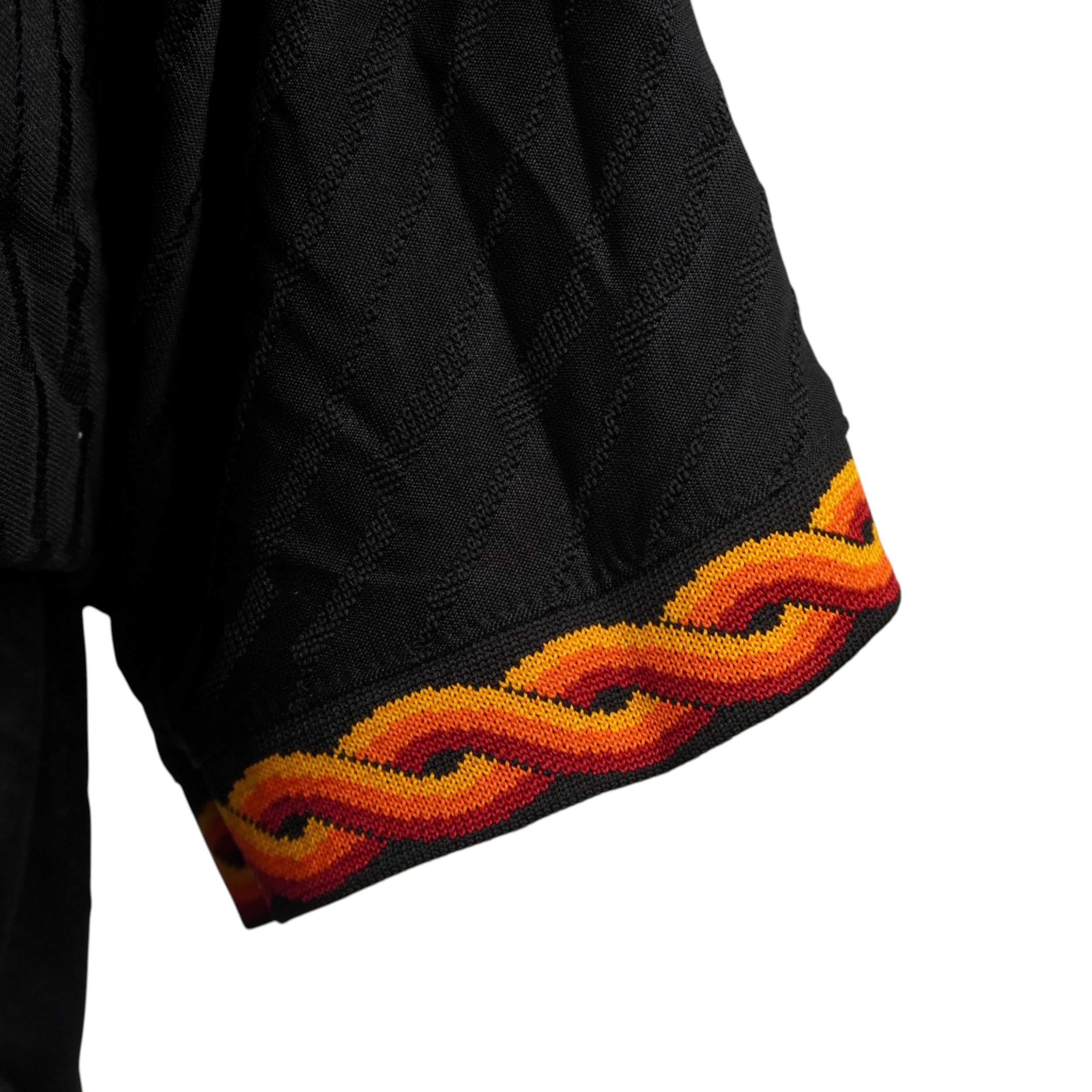 Particolare del bordo manica della maglia della Roma con motivo geometrico intrecciato nei toni del giallo, arancione e rosso
