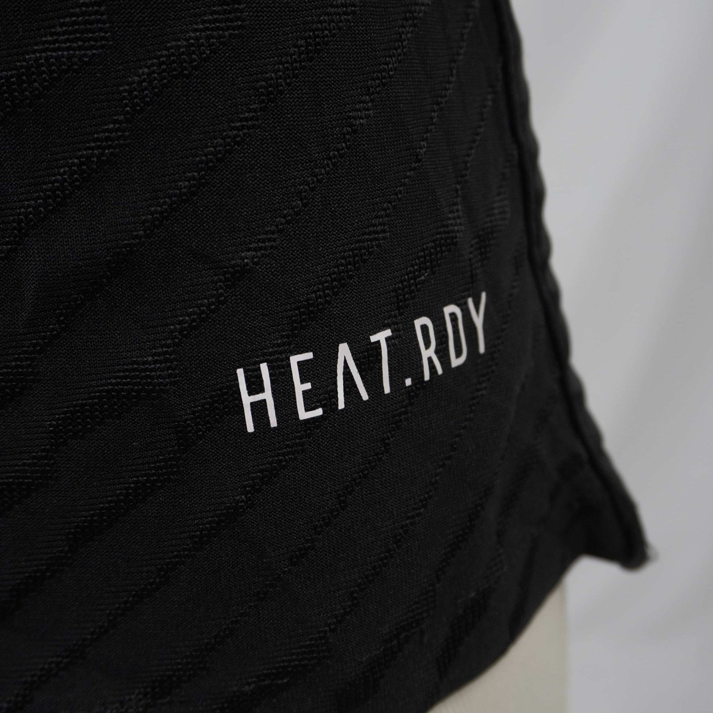 Dettaglio della stampa termotrasferita della tecnologia di ventilazione premium adidas HEAT.RDY sul bordo inferiore del tessuto