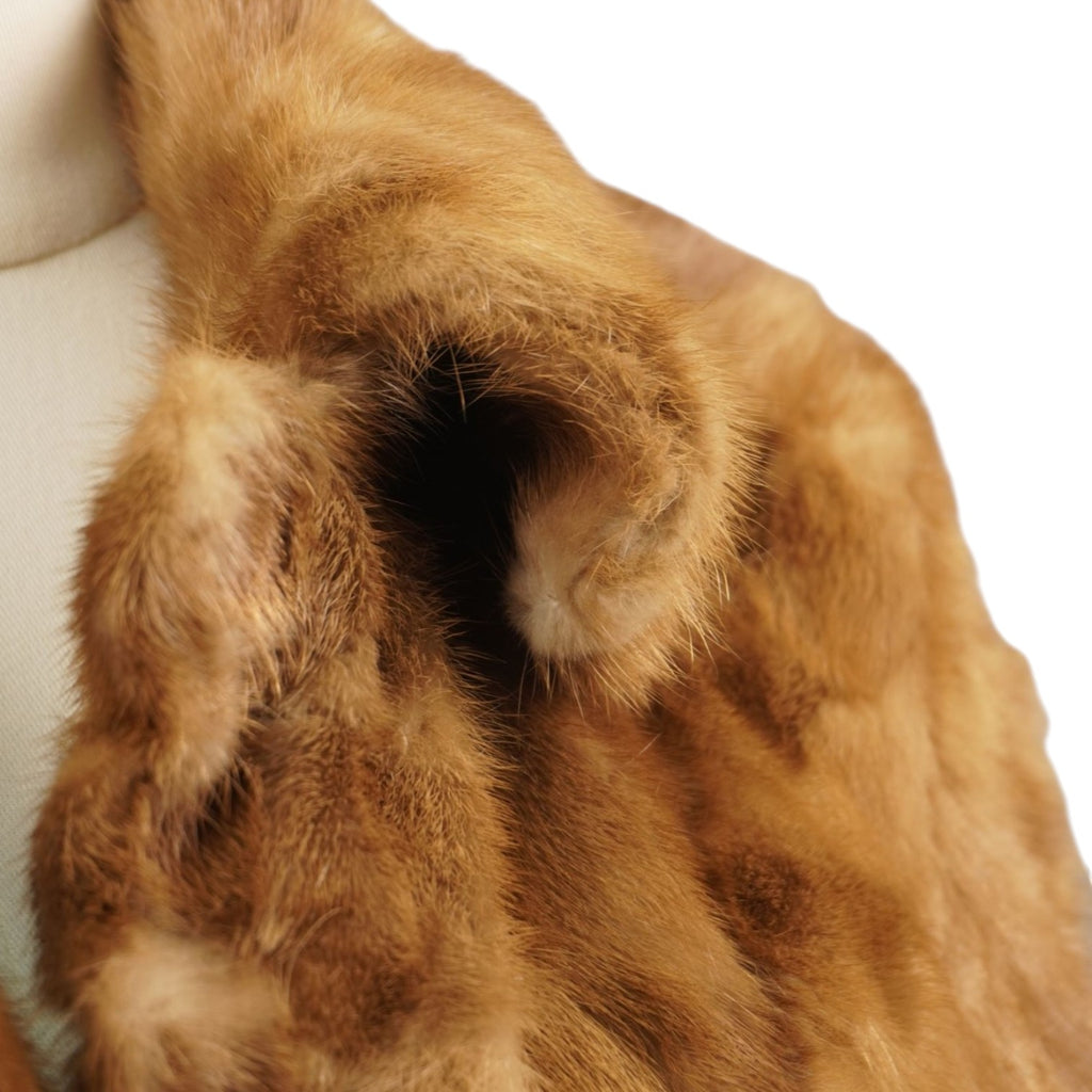 Dettaglio ravvicinato della texture morbida e lucente della pelliccia di visone color biondo oro.