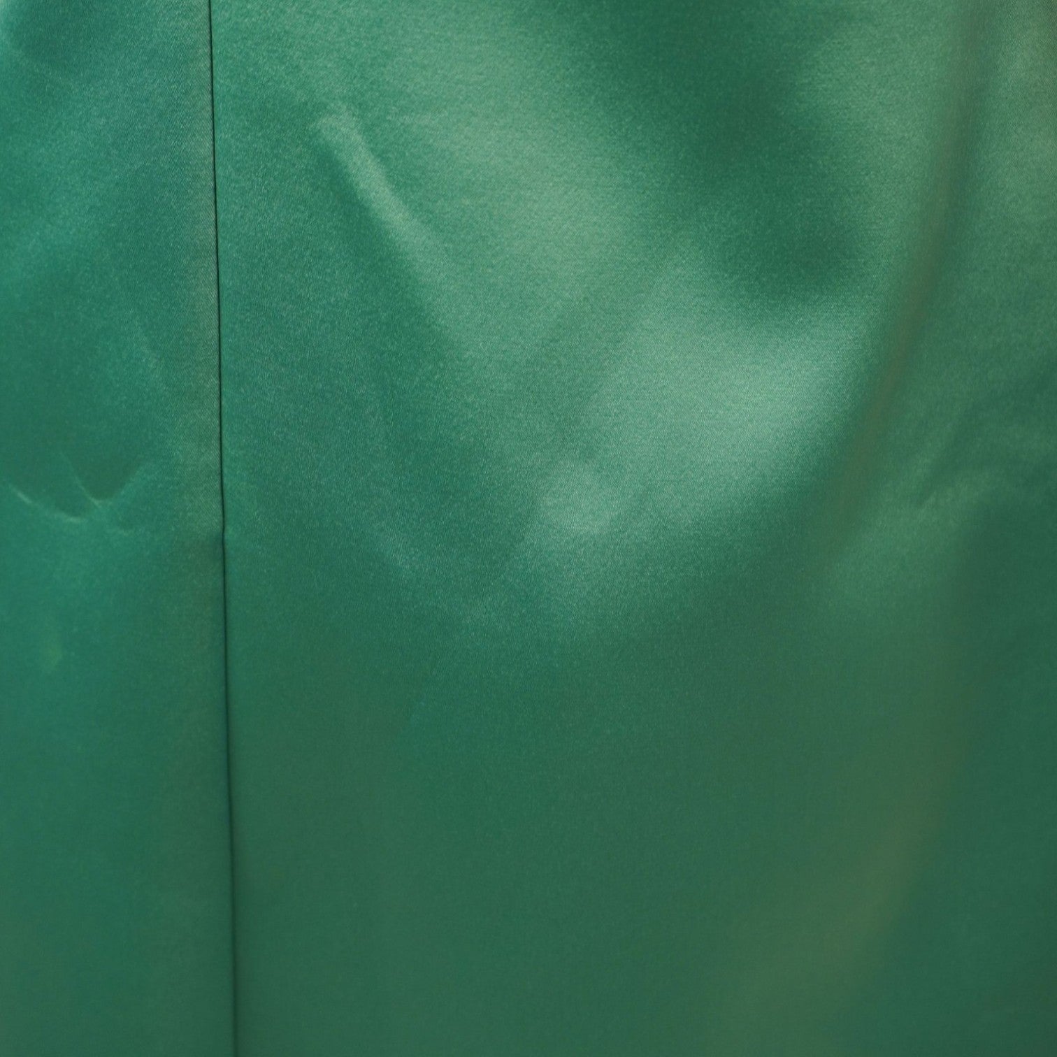  Dettaglio macro della superficie liscia e lucida del tessuto satinato verde smeraldo dell'abito.
