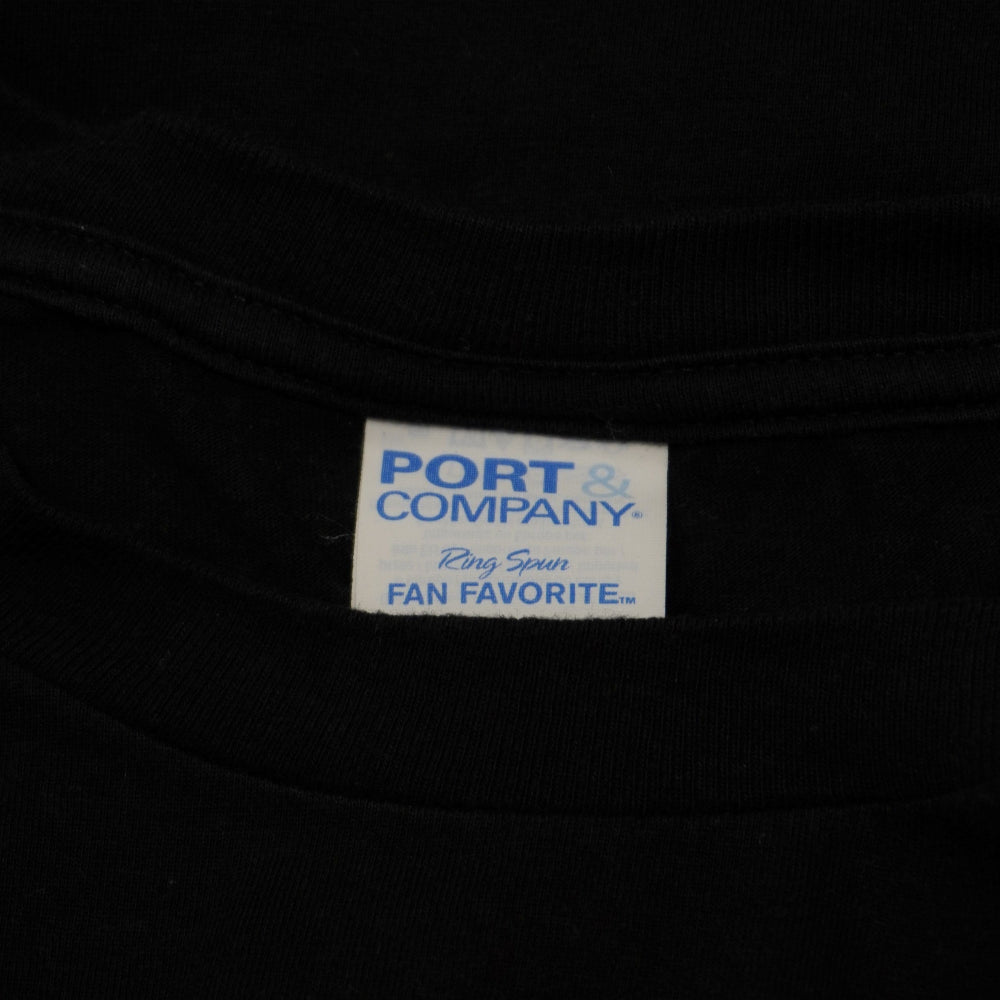Dettaglio dell'etichetta bianca Port and Company Fan Favorite sul colletto interno della maglia.