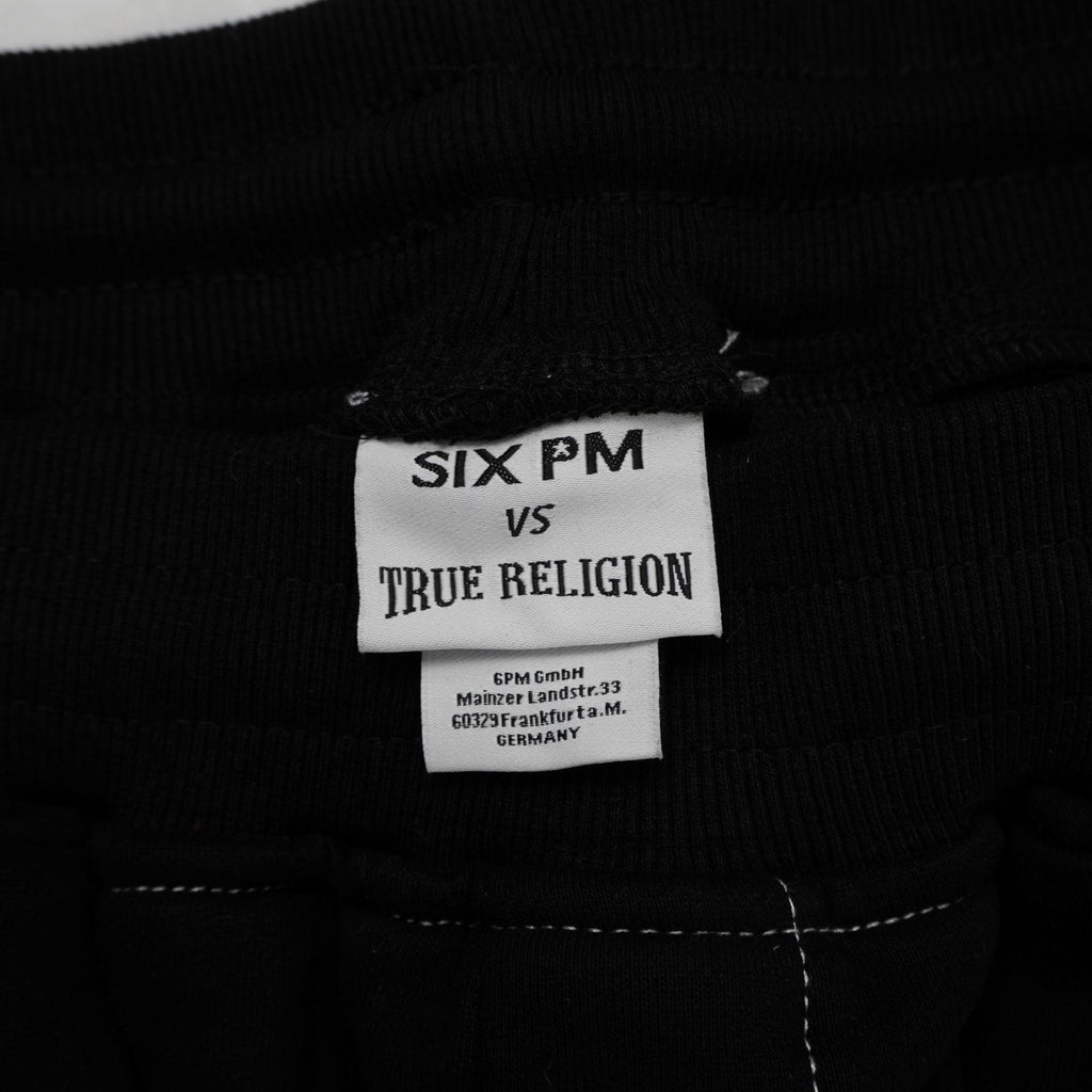 Etichetta bianca rettangolare cucita all'interno del collo con il branding 6PM by True Religion.