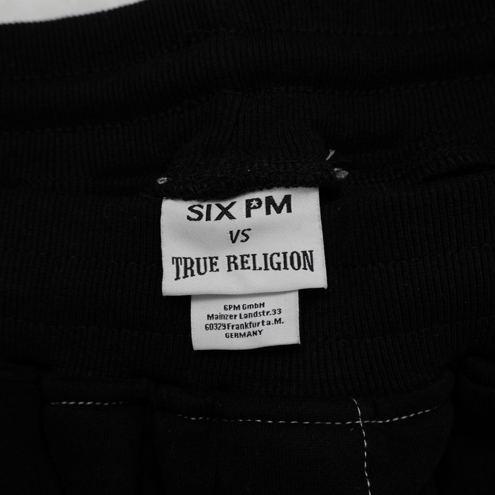 Etichetta bianca rettangolare cucita all'interno del collo con il branding 6PM by True Religion.