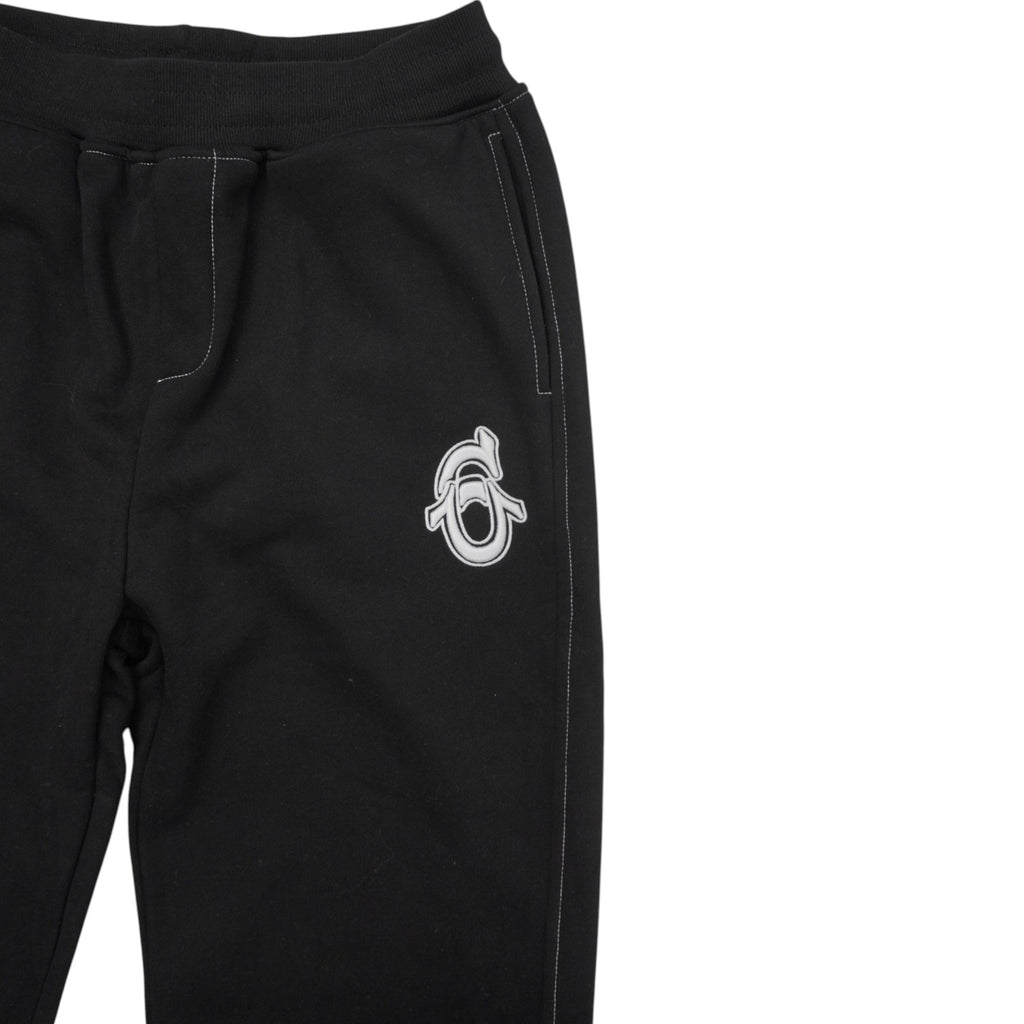 Ingrandimento del logo monogramma bianco ricamato sul davanti dei pantaloni della tuta.