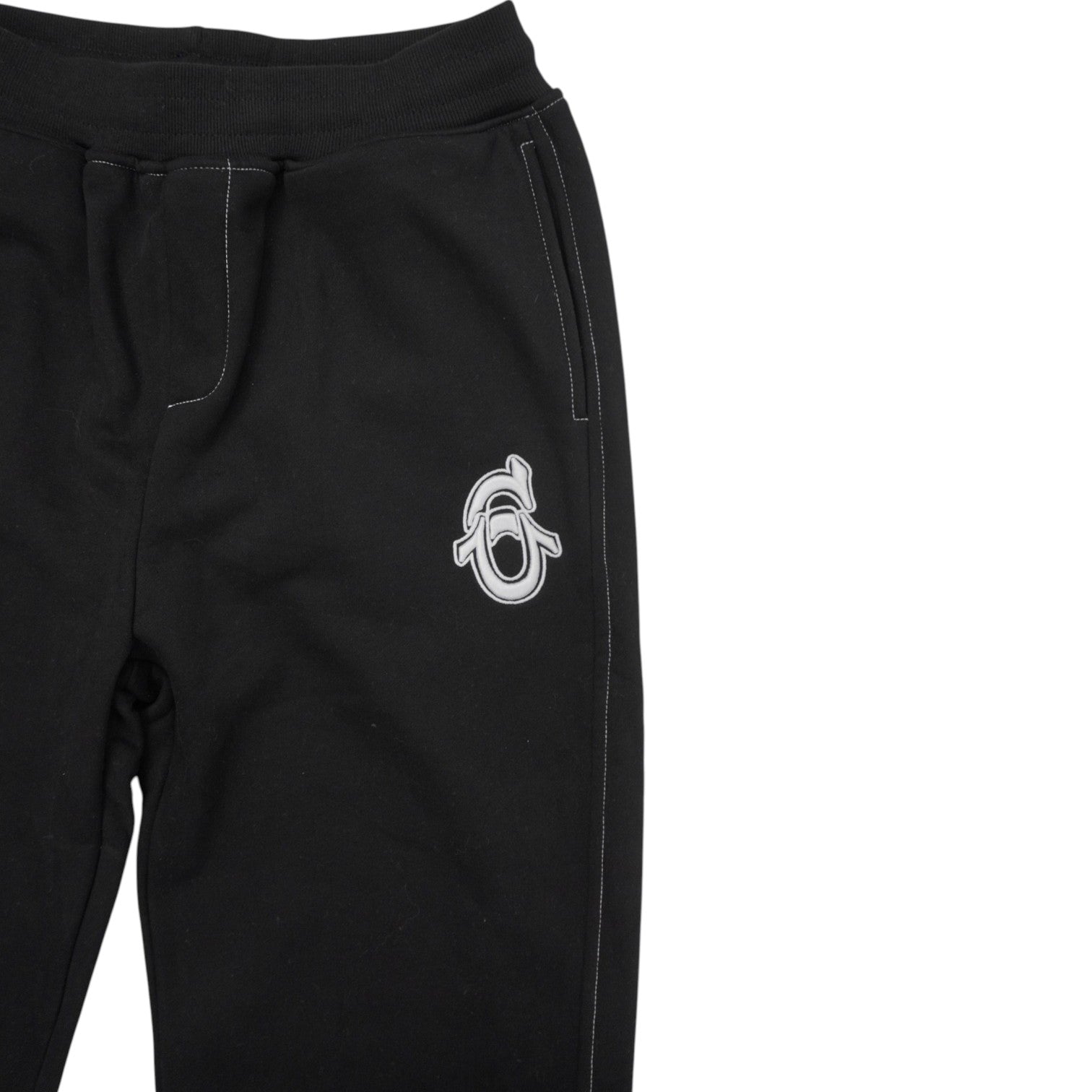 Ingrandimento del logo monogramma bianco ricamato sul davanti dei pantaloni della tuta.