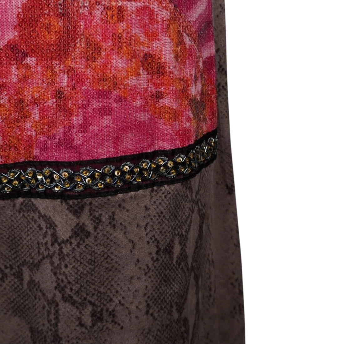 Dettaglio ravvicinato della passamaneria centrale a treccia nera e oro con strass incastonati che divide il pannello con paillettes fucsia dalla gonna pitonata.