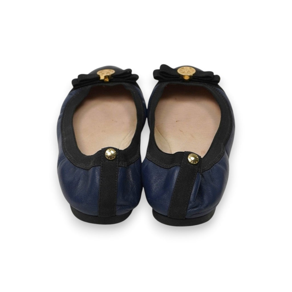  Vista posteriore del tallone arricciato ed elasticizzato delle ballerine blu con fettuccia nera e borchia decorativa oro.